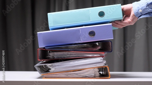 Bild auf Leinwand Human hand arranging an extensive pile of multicolored office ring binders fille