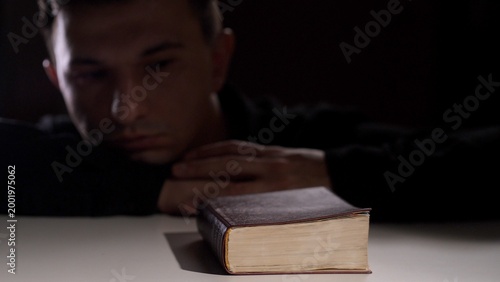 Quadro su tela Man dimly lit, resting his head on his hands and appearing contemplative while a