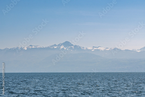 Sommets alpins se détachant au-dessus du lac Léman dans une brume légère.