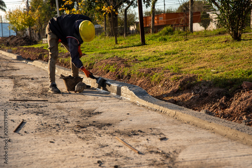 Foto Construction worker finishing concrete curb with a brush and mortar on a new roa