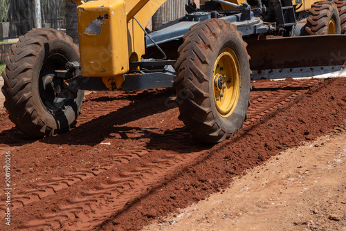 Obraz na płótnie Close-up of Road Grader Tires Working on a Red Dirt Road Surface