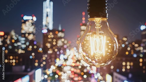 A glowing vintage light bulb hangs in focus against a blurred cityscape at night, symbolizing innovation and urban energy.