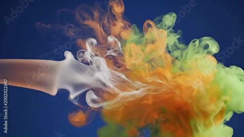 A vibrant and dynamic abstract image showcases swirling orange and green ink blooming in water against a deep blue background, creating a mesmerizing display of color and motion.