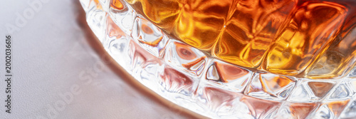 Wide whiskey glass macro with ice and amber liquid, luxury bar banner with copy space