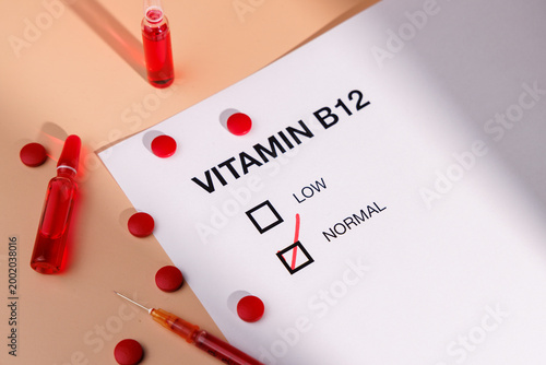 Tableau sur toile Vitamin B12 vials with red tablets and medical form on cream gradient for metabolic health, energy recovery and professional wellness