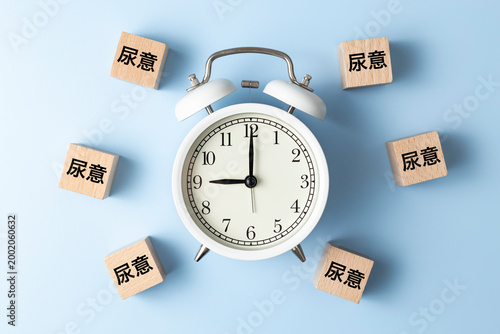 「尿意」と書かれたのブロックと目覚まし時計