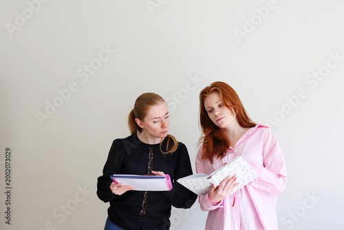 Girls with notebooks talking and sharing ideas, education and collaboration theme.