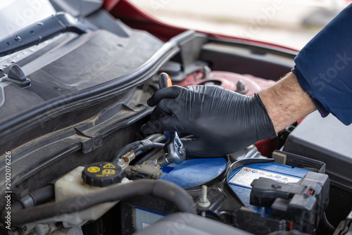 Mechanic using ratchet wrench on car battery during maintenance and repair process