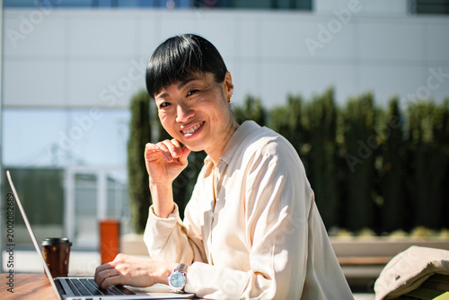Smiling businesswoman working on laptop outdoors