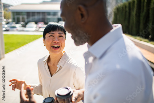 Smiling coworkers chatting over coffee outside office