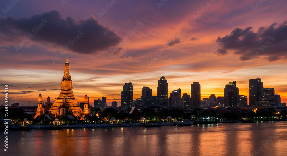 Fototapeta premium Evening cityscape with illuminated temple and modern buildings against sunset sky