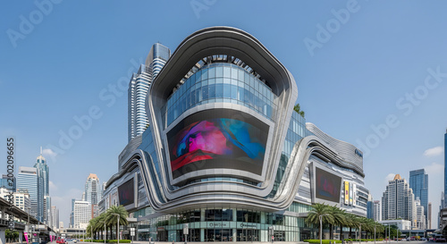 Modern architectural building with glass facade and digital display against blue sky