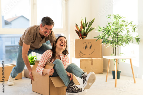 Two people play with cardboard boxes in a bright living room during a fun moving day activity