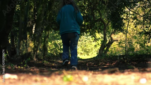 Woman running through woodland in dappled summer sunshine