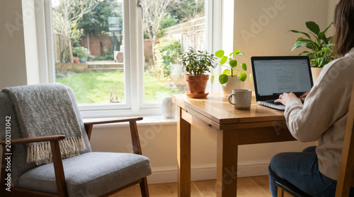 Woman working from home office with laptop and plants
