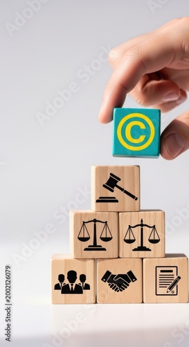 A hand places a copyright symbol cube atop a stack representing legal principles like justice and agreements.