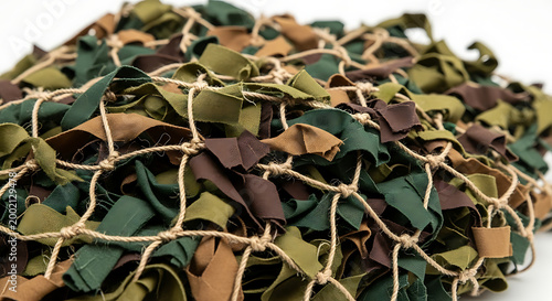 Close-up of a textured camouflage net with green and brown strips isolated on white background