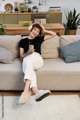 Fotografie Young beautiful woman enjoys a relaxing moment at home while using her phone and