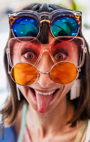 The girl is laughing and having fun. The girl is wearing a lot of sunglasses and laughing. Fun and madness.