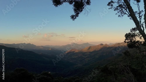 Panorama aéreo das montanhas de Minas Gerais com luz dourada do pôr do sol destacando o relevo e a vegetação da Serra da Mantiqueira.
