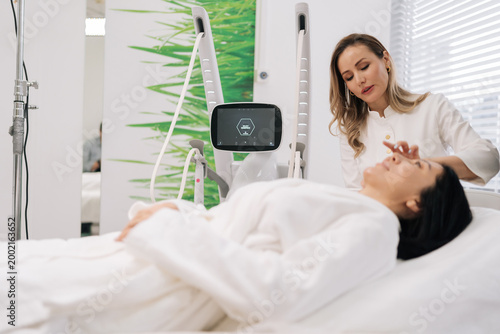 Fotografia Female cosmetologist performing microneedling mesotherapy treatment on female client face, focusing on skin rejuvenation, anti-aging, aesthetic care in beauty clinic