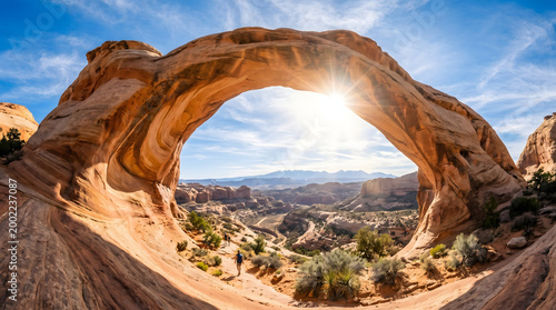 Natural arch rock formation in desert landscape with blue sky and sun rays shining through transparent background