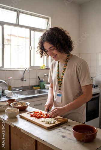 Young man with curly hair chopping tomatoes