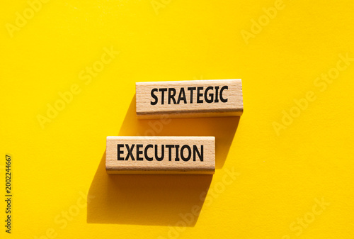 Strategic execution symbol. Concept word Strategic execution on wooden blocks. Beautiful yellow background. Business and Strategic execution concept. Copy space