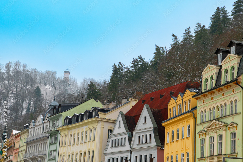 Fototapeta premium Karlovy Vary (Karlsbad) colorful houses and historic architecture in Czech Republic spa town winter cityscape with forest and tower