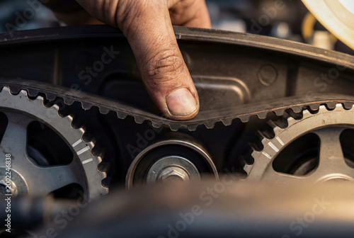 Mechanic Hand Checking Timing Belt Tension on Engine Pulleys