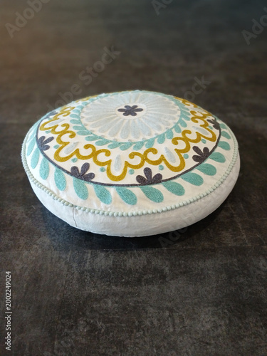 Decorative round cushion on a gray background. Moroccan Round Hippie Floor Pillow Cover. Boho Mandala Pattern Pouf. Close-up of cotton cushion cover. Home decor.
