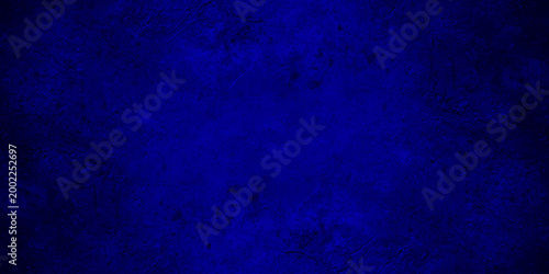 Dark blue grunge texture background with vignetting, abstract navy blue mottled wall surface