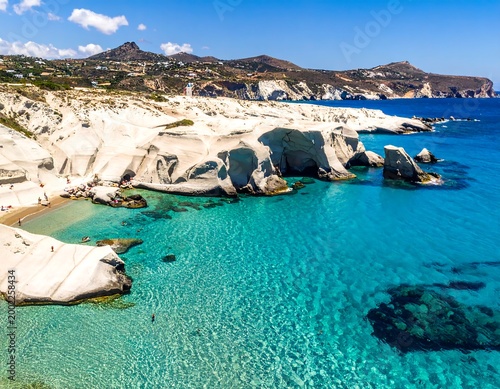 Azure sea meets white cliffs and sunbathers by rocky shore