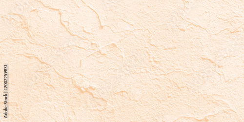 Pale peach textured stone wall background with subtle grain and natural plaster finish for minimalist interior design