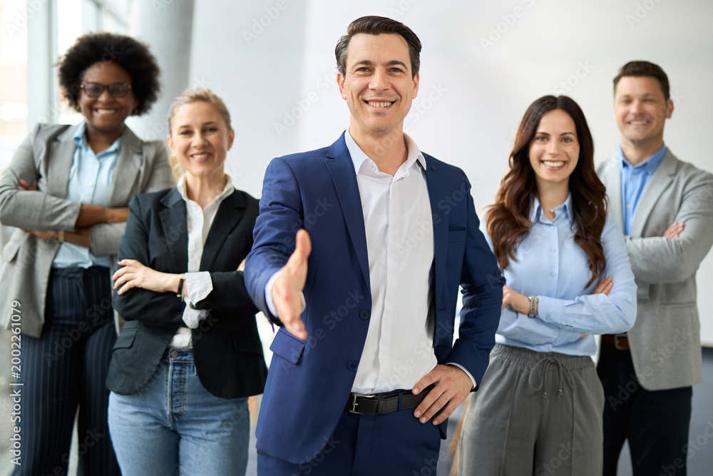 Obraz premium Portrait of happy male CEO offering a handshake in the office and looking at camera