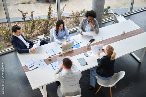 High angle view of group of diverse business people talking during a meeting in a modern office.
