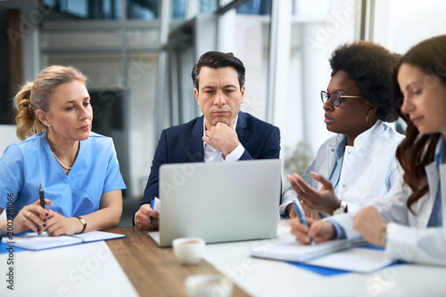 Mid adult businessman having a meeting with group of doctors in hospital