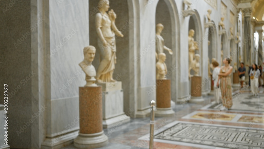 Fototapeta premium Blurred museum interior with classical marble statues, arches and polished mosaic floor in shallow bokeh; background backdrop copyspace calm.