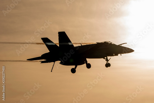 Foto Silueta de avión de combate aterrizando al amanecer con tren de aterrizaje, gancho y sonda de repostaje desplegados