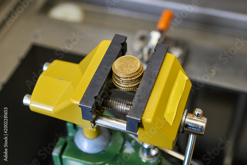 Картината върху платно Euro coins clamped in a yellow metal vise