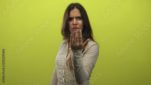 Canvas Print Woman pointing finger at camera with furrowed brow and stern face in lime green studio; accusation demand accountability