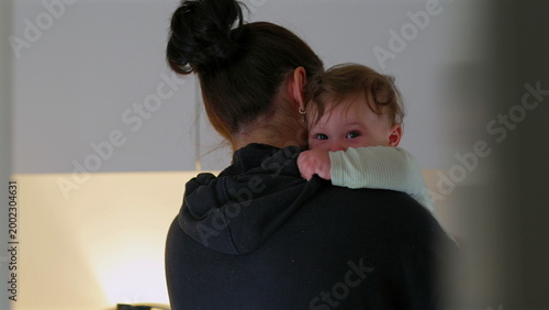 Foto Mother holding baby over shoulder in quiet kitchen, child resting with calm expr