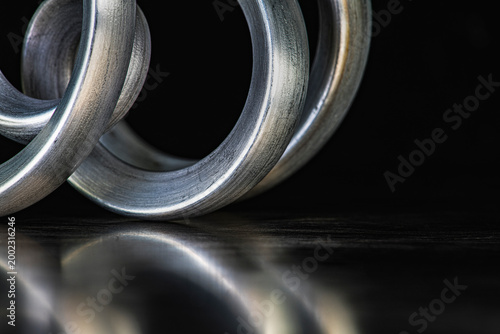 Closeup of bent aluminum rods on a reflective metal surface, showing aluminum structure and plasticity as raw material of light metal industry