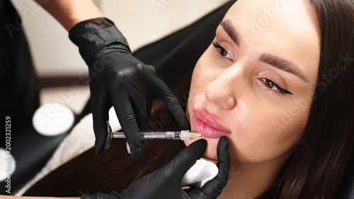 Photos Young woman undergoing lip augmentation procedure with dermal fillers in beauty clinic