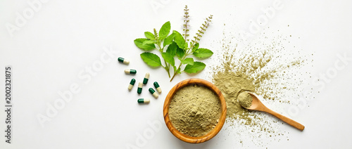 herbal medicine concept with tulsi leaves, powder, and capsules on white background