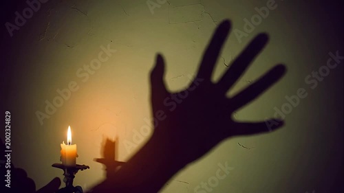 Spooky Halloween text appearing with a flickering candle and ominous shadow hand on a cracked wall for a horror mystery concept