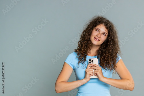 Photos Young woman joyfully reads lovely romantic text message on smartphone with pleased, heartfelt emotional expression