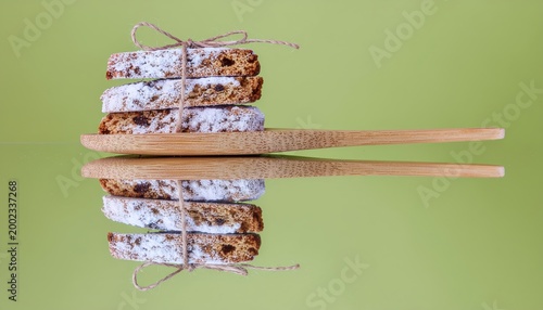Artisanal biscotti stack on bamboo utensils, dusted with powdered sugar on vibrant green