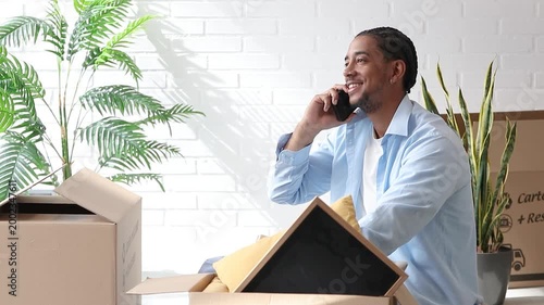 young latino man packing for a move while talking on the phone, moving and transportation, new house