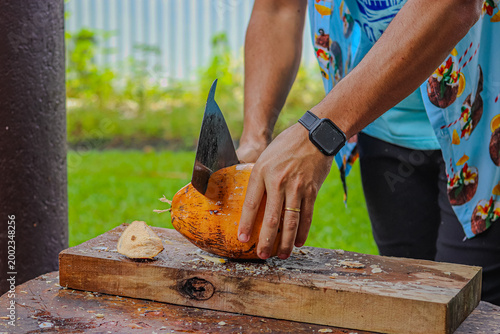 man cuts a coconut